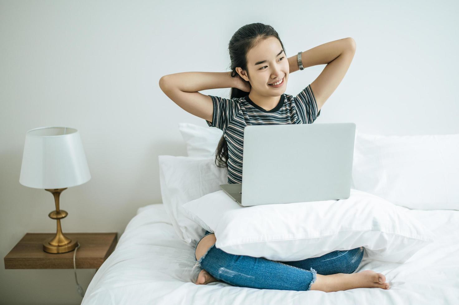 een jonge vrouw die op haar laptop in bed speelt foto