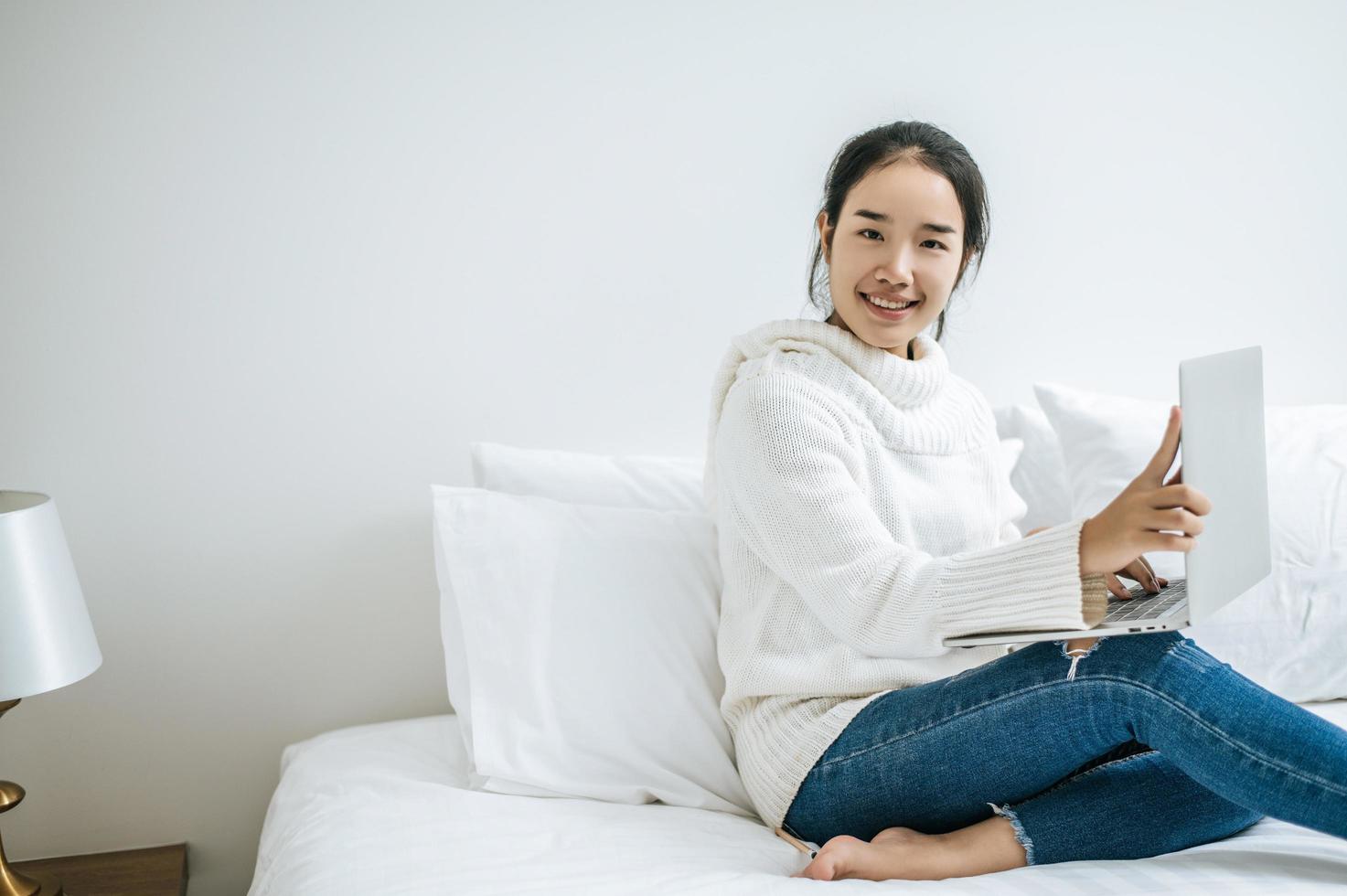 jonge vrouw die een wit overhemd draagt dat op haar laptop speelt foto