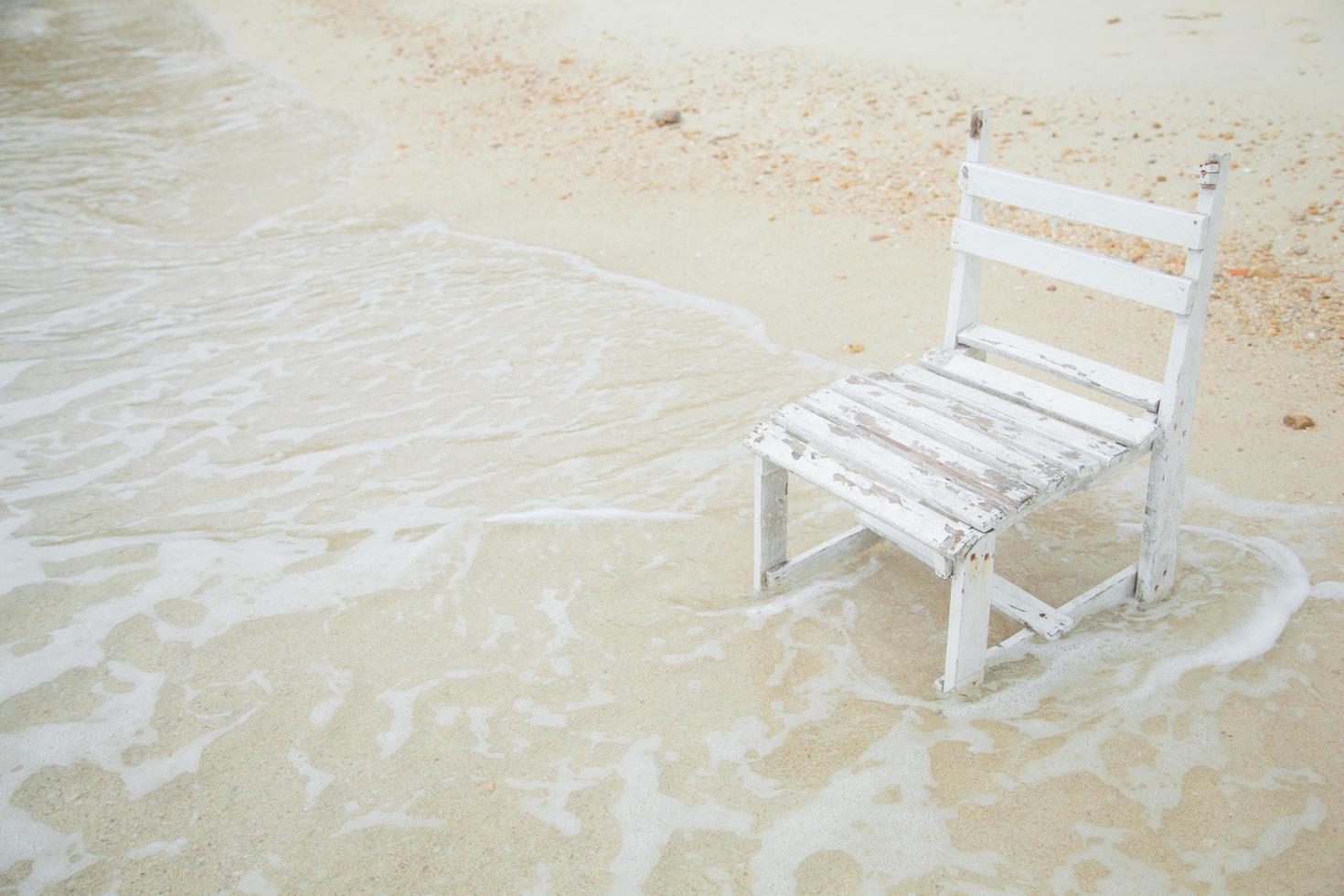witte houten stoel aan zee foto