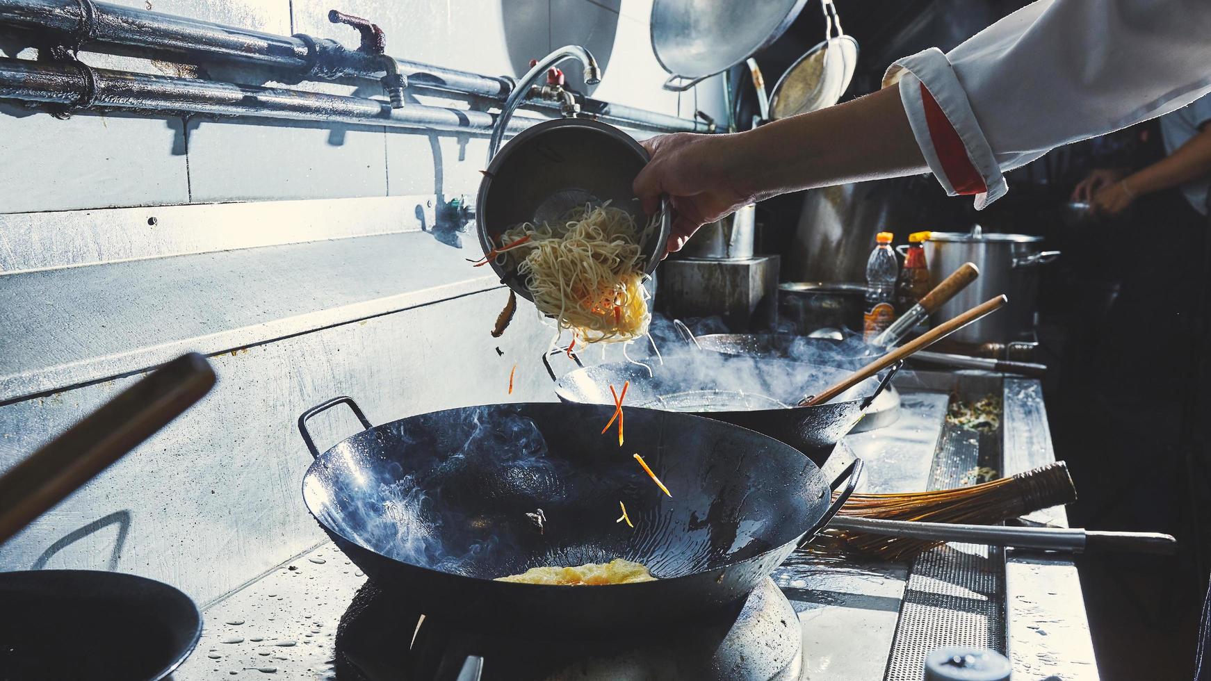 chef-kok die voedsel in de wok kookt foto