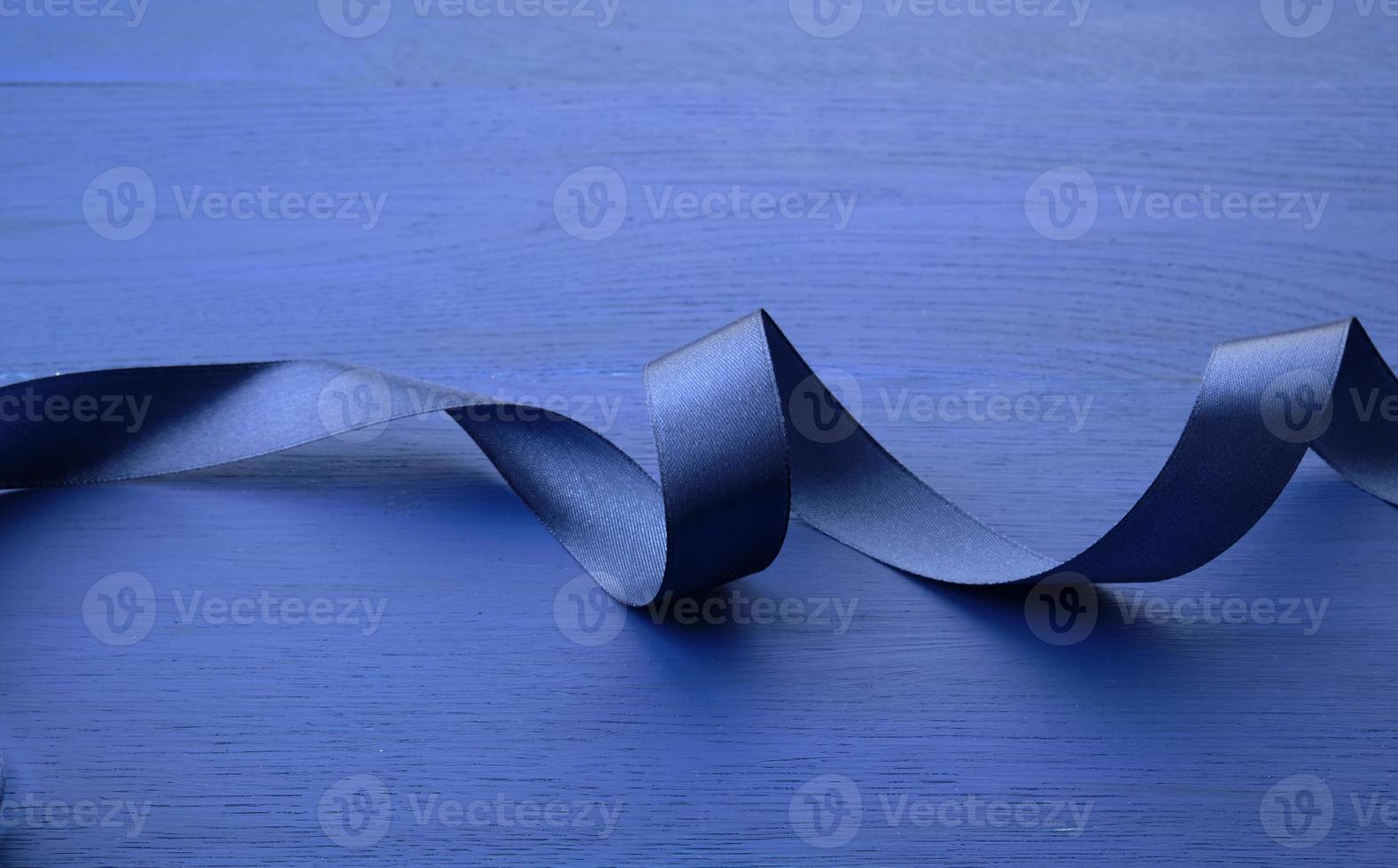 blauw zijde dun lint gedraaid Aan een blauw houten achtergrond foto