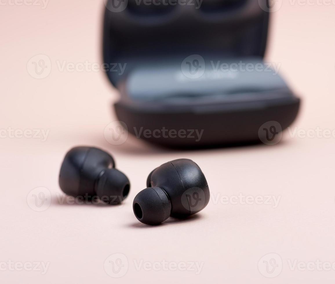 paar- van zwart draadloze weinig oortelefoons en een opladen doos foto
