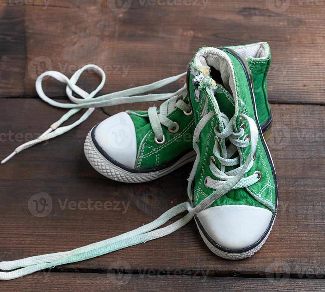 versleten oud textiel groen sportschoenen met losgemaakt wit veters foto
