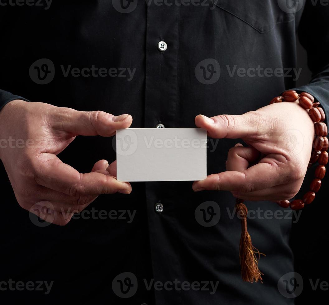 twee mannetje handen Holding een rechthoekig blanco wit papier bedrijf kaart, een Mens vervelend een zwart overhemd foto