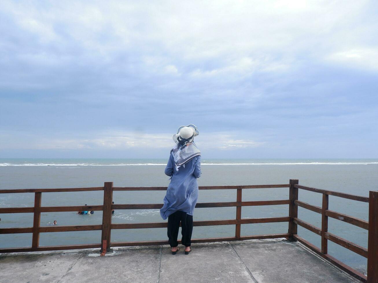 terug van de vrouw in de hoed Aan de tropisch strand wie was op zoek Bij de lucht en de zee van de brug. zee visie foto