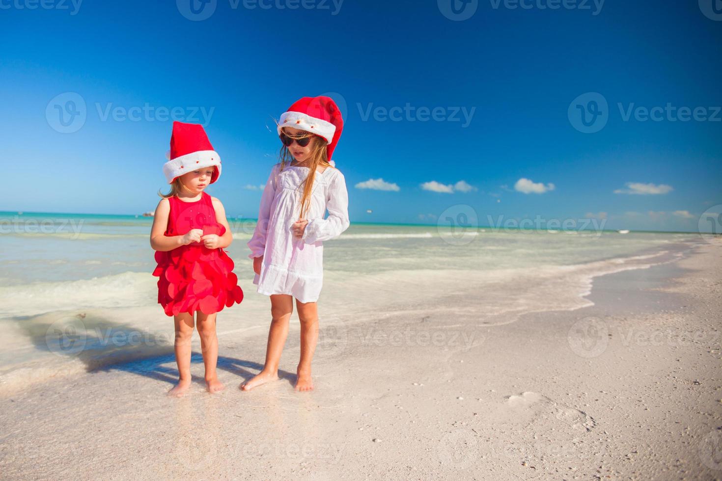 terug visie van weinig schattig meisjes in Kerstmis hoeden Aan de exotisch strand foto