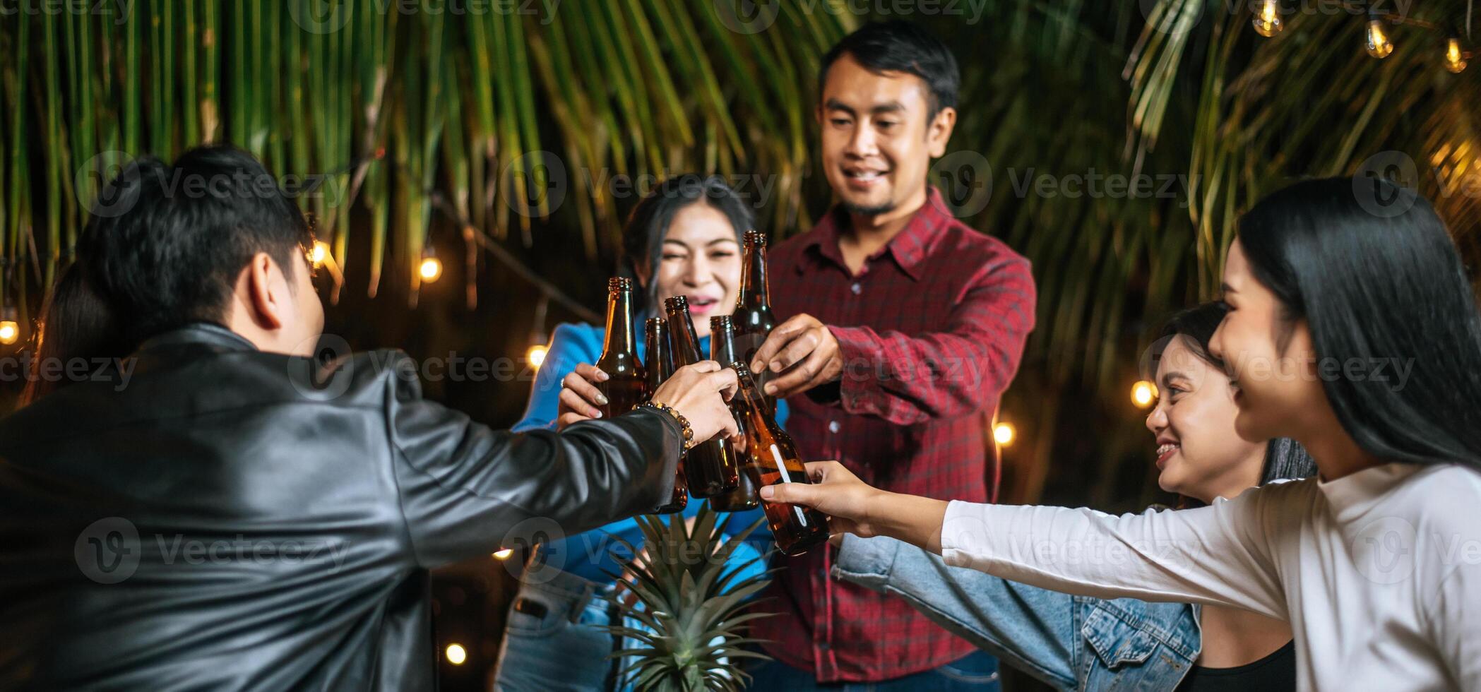 portret van gelukkig Aziatisch vrienden hebben avondeten partij samen - jong mensen zittend Bij bar tafel roosteren bier bril avondeten buitenshuis - mensen, voedsel, drinken levensstijl, nieuw jaar viering concept. foto