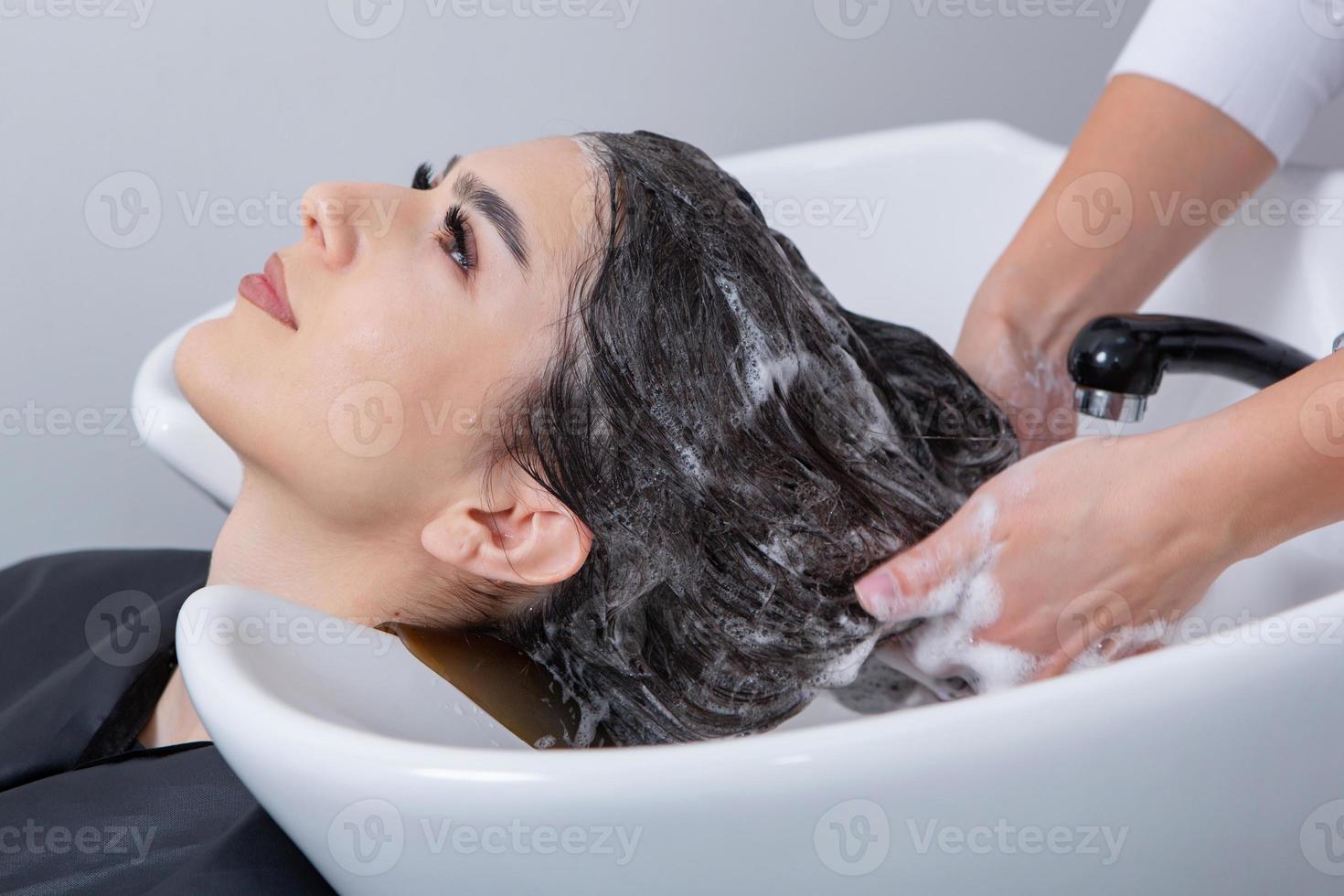 professioneel kapper het wassen haar- van jong vrouw in schoonheid salon. dichtbij omhoog van vrouw haar- in schoonheid salon, kapsel concept foto