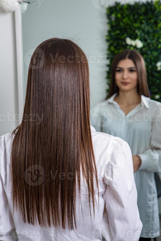 een Rechtdoor gezond brunette haar- dat heeft ondergaan de haar- rechttrekken procedure. Rechtdoor, glimmend en gezond brunette haar- foto