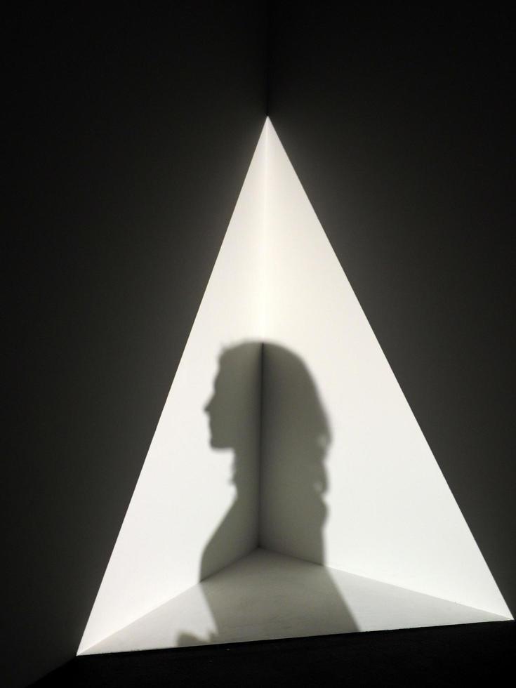 schaduw van een persoon in een driehoek van licht foto
