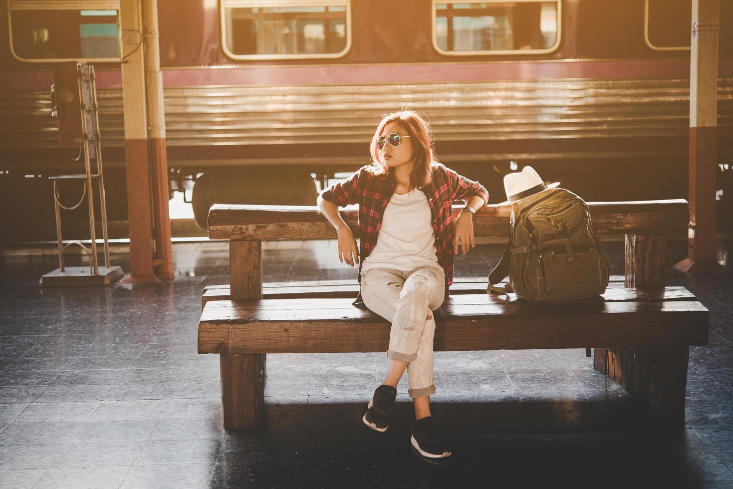 jonge hipster toeristische vrouw met rugzak zitten in het treinstation foto