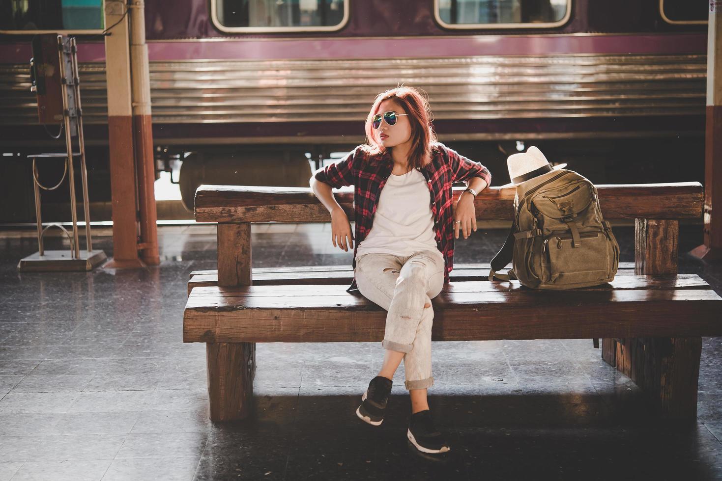 jonge hipster toeristische vrouw met rugzak zitten in het treinstation foto