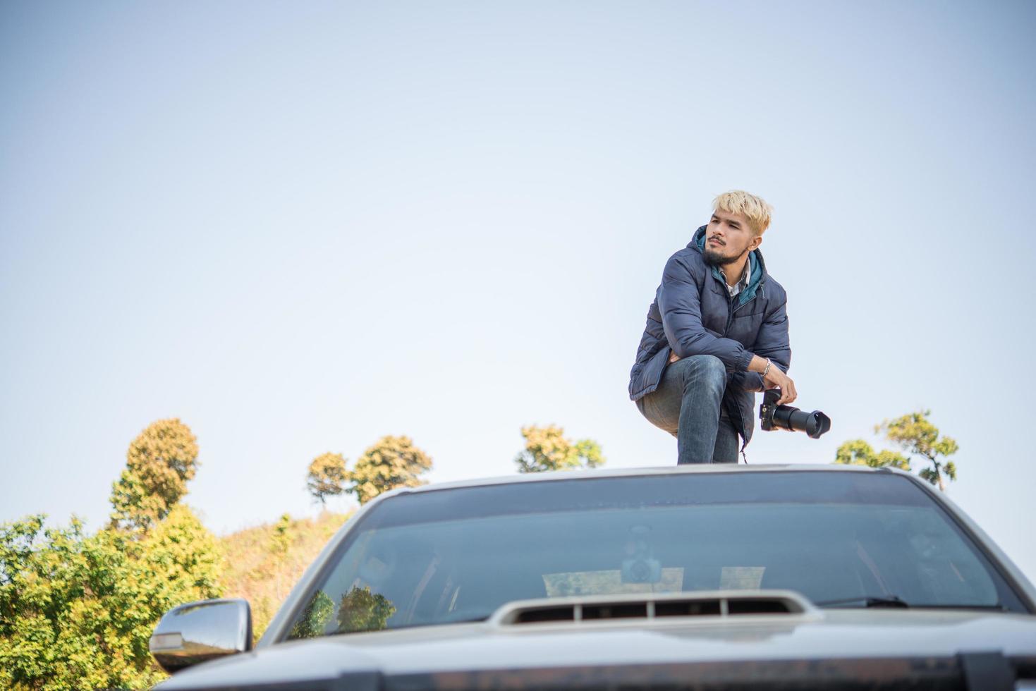 jonge fotograaf zittend op zijn pick-up truck fotograferen van een berg foto