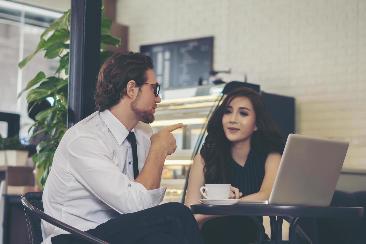 gelukkige collega's ontmoeten elkaar in café die op laptop werkt foto