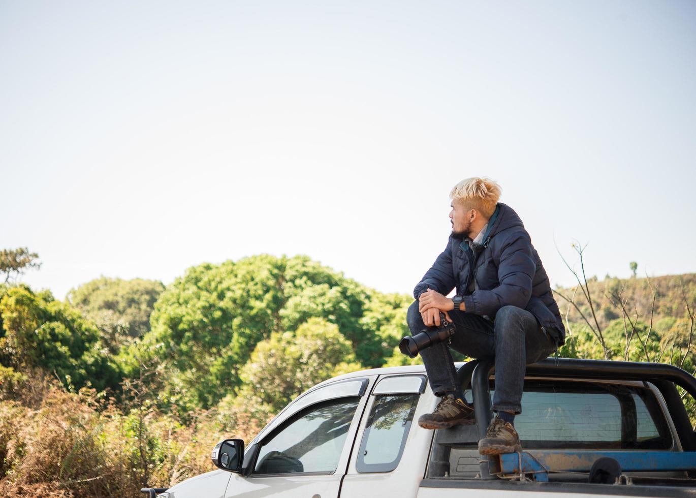 jonge fotograaf zittend op zijn pick-up truck foto