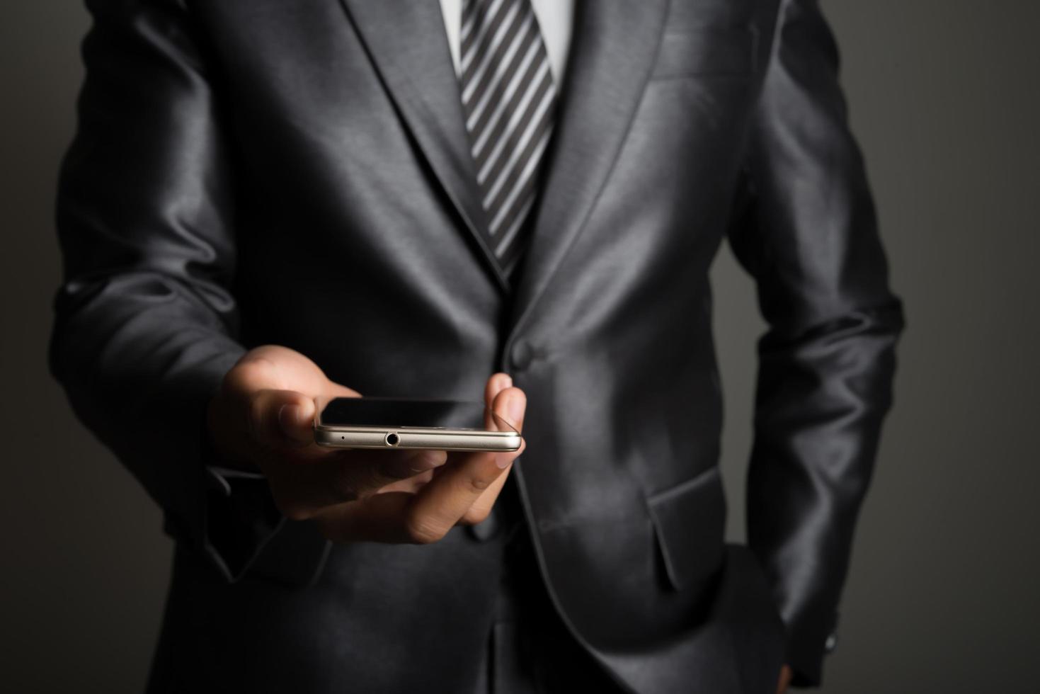 jonge zakenman met behulp van mobiele telefoon geïsoleerd op zwarte achtergrond foto