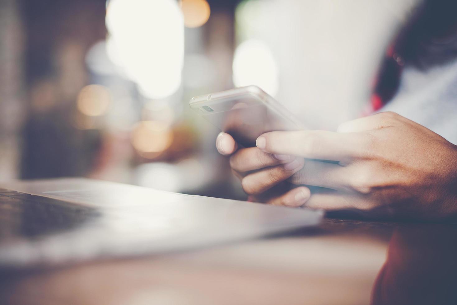 close-up van een vrouw die werkt met haar smartphone in een café foto