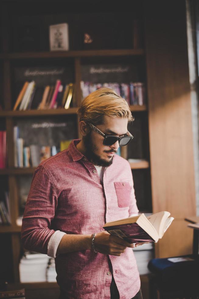 jonge bebaarde hipster lezen van een boek in een café foto