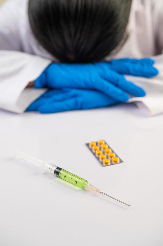 wetenschapper aan tafel met vaccins en medicijnen foto