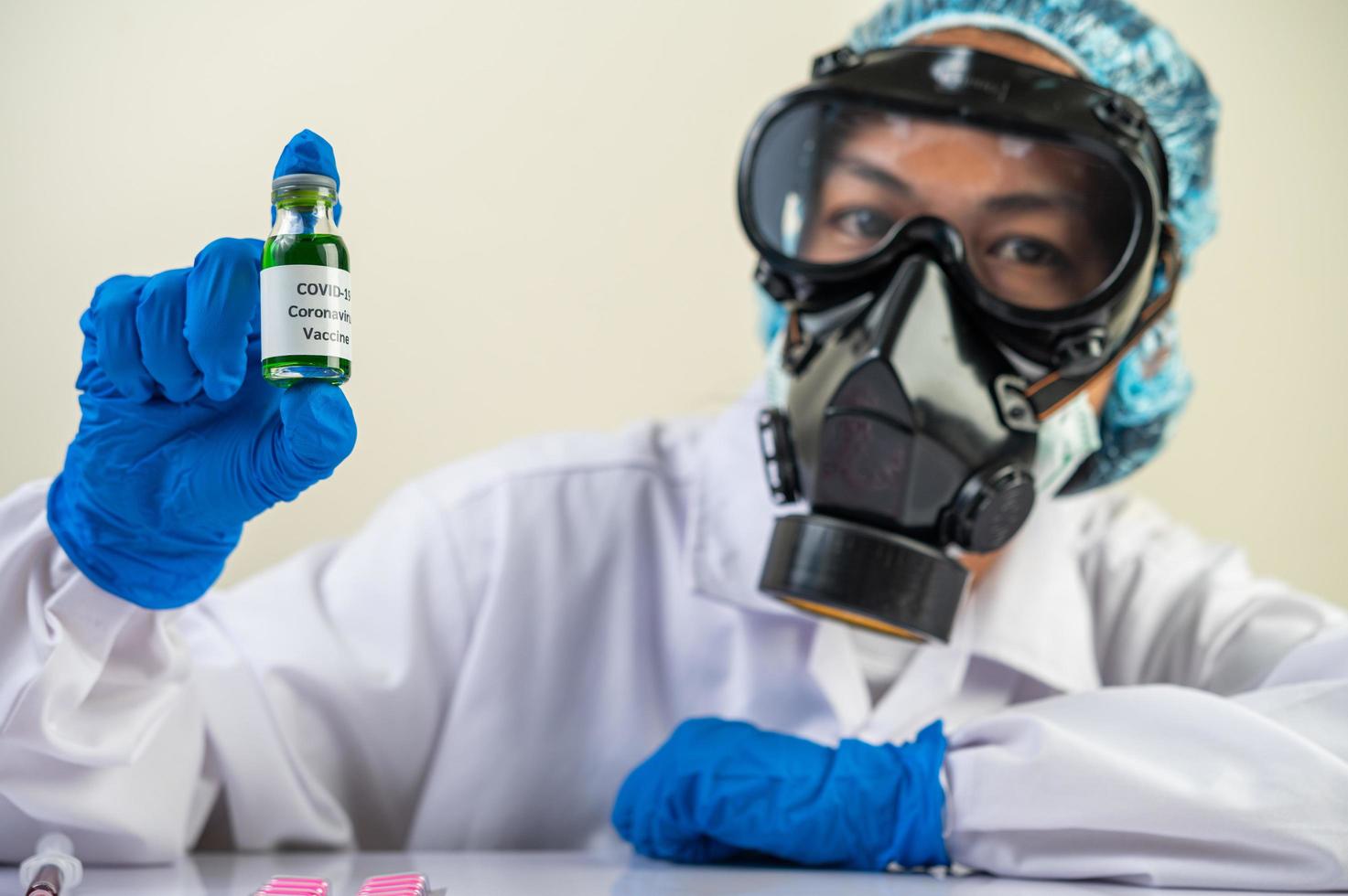 een wetenschapper met masker en handschoenen draagt flesjes met vaccins ter bescherming tegen covid-19 foto