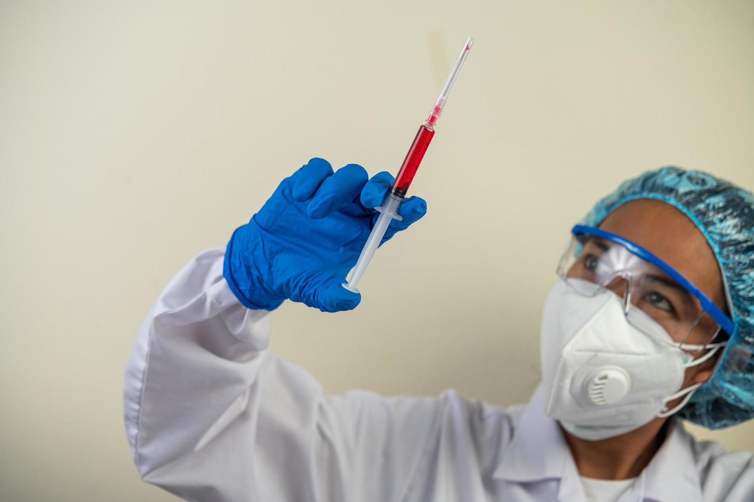 wetenschapper die beschermende maskers draagt en handschoenen die een injectiespuit met een vaccin vasthouden om covid-19 te voorkomen foto