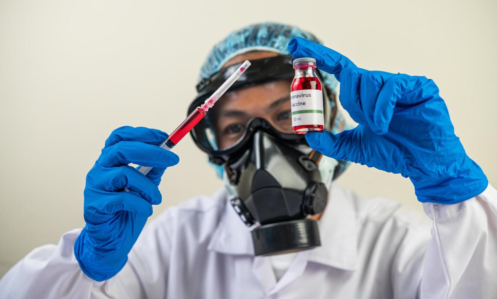 wetenschapper die beschermende maskers draagt en handschoenen die een injectiespuit met een vaccin vasthouden om covid-19 te voorkomen foto