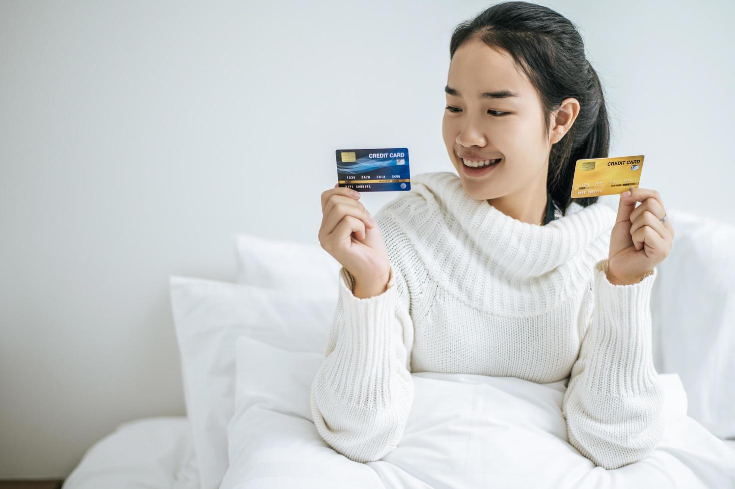 jonge vrouw met een creditcard lachend op bed foto