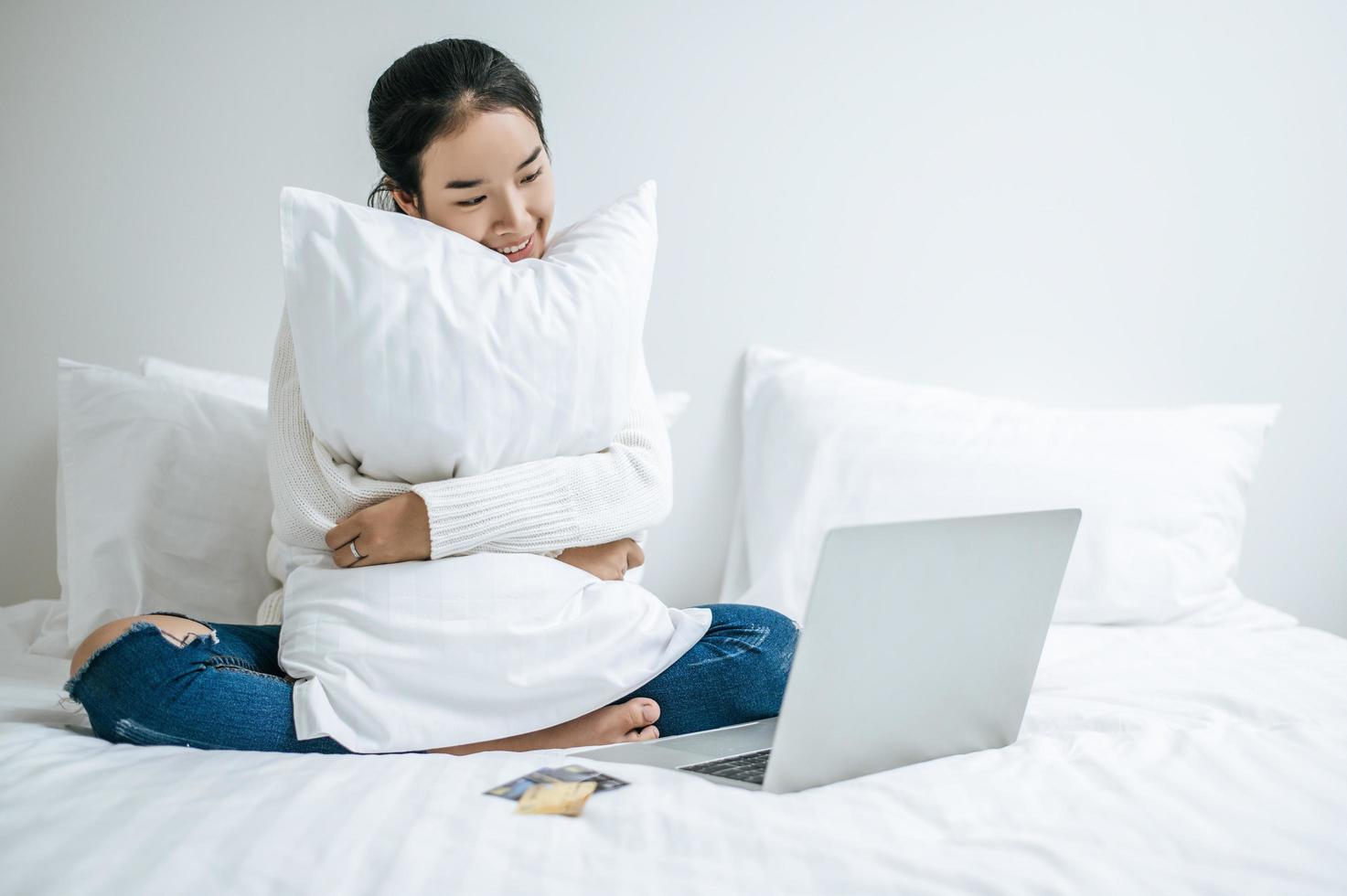 jonge vrouw zittend op haar bed en knuffelen kussen foto