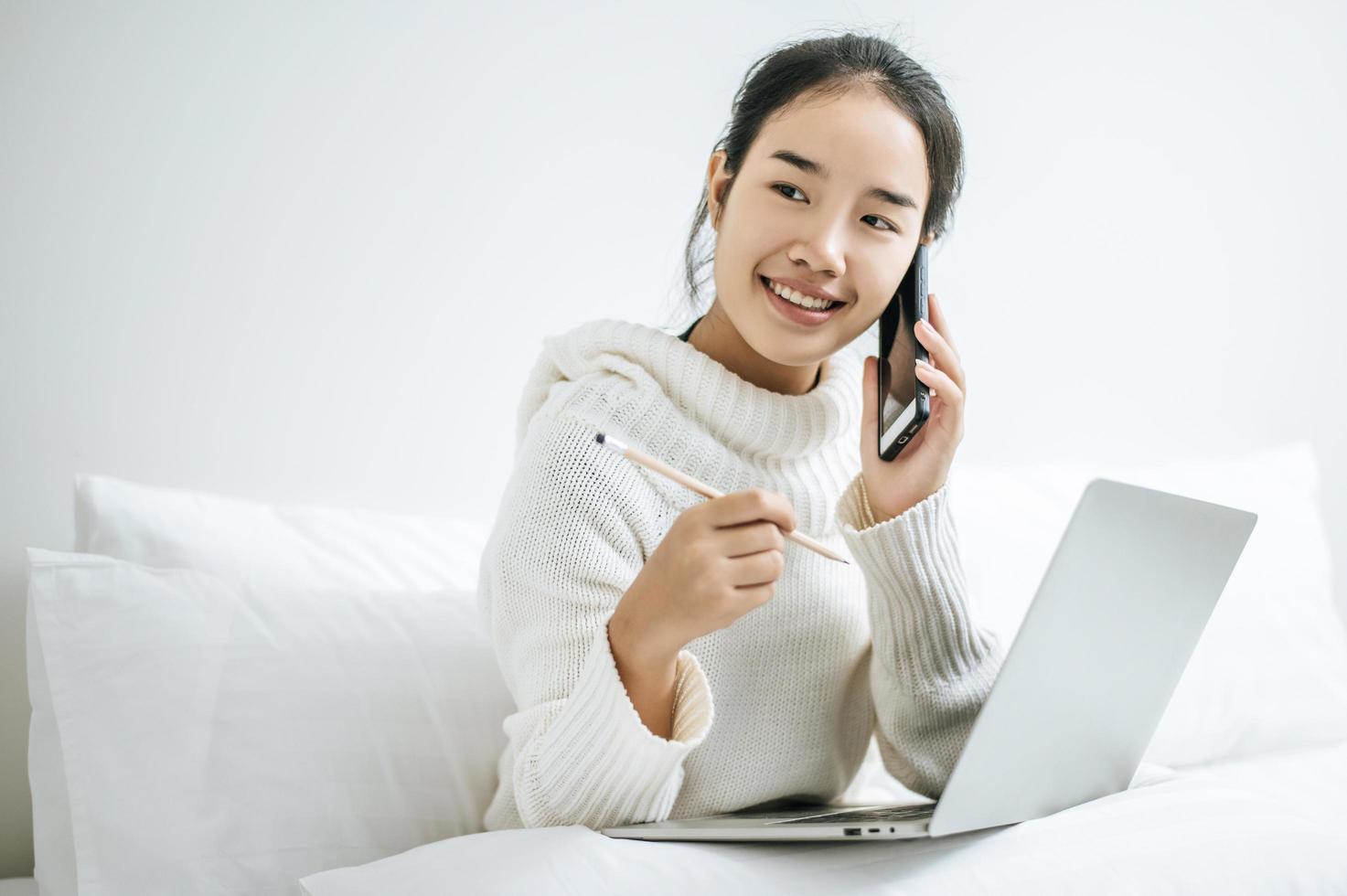 vrouw spelen op haar laptop en praten over de telefoon foto