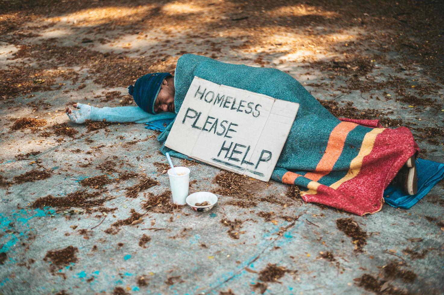 bedelaar slaapt op straat met berichten over daklozen, help alstublieft foto