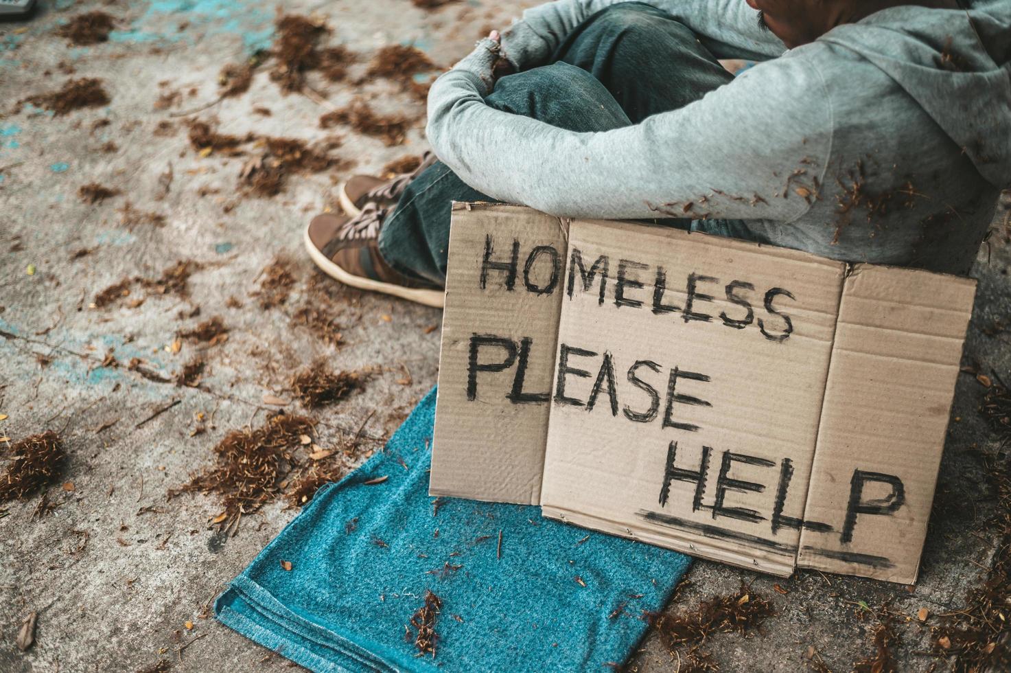 bedelaar slaapt op straat met berichten over daklozen, help alstublieft foto
