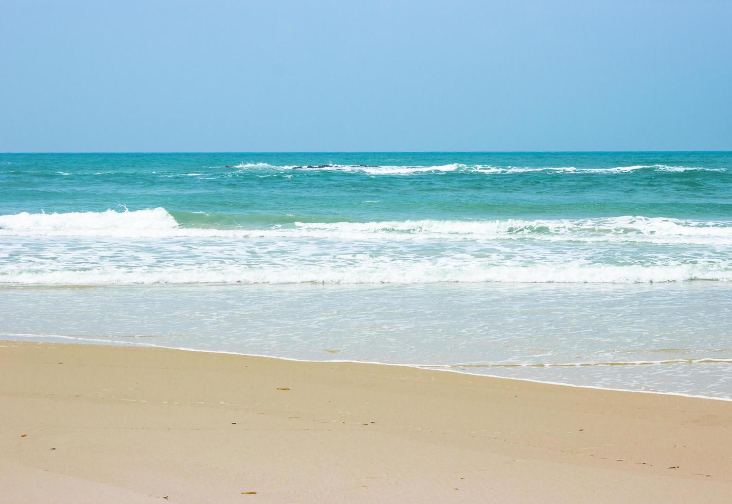 oceaangolven op strand met heldere blauwe hemel foto