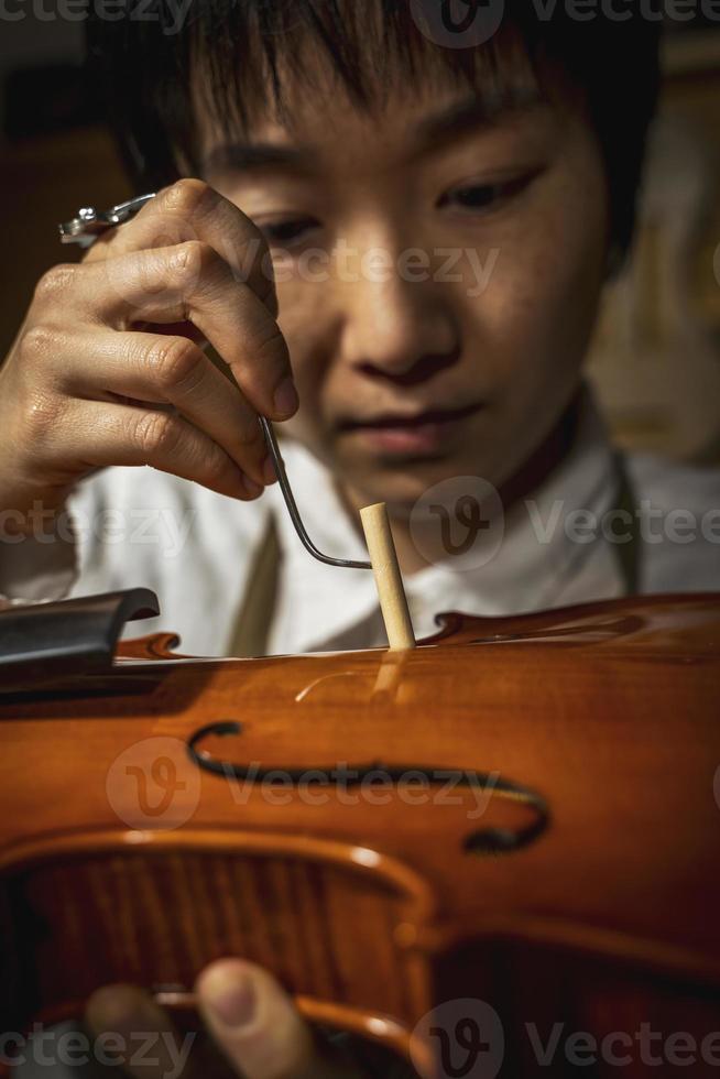 jong Chinese viool maker Bij werk in haar werkplaats foto