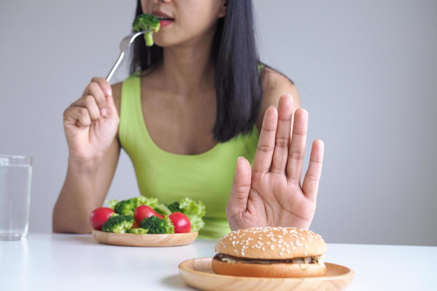 gezond Dames Kiezen naar eten groente dienbladen en weigeren naar eten hamburgers. foto