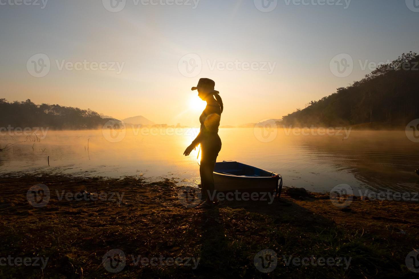 Dames staand naast een boot naar de kust Bij de reservoir gedurende de zonsopkomst, harak Woud park huai naam Mens reservoir loei Thailand 21 jan 2023 foto