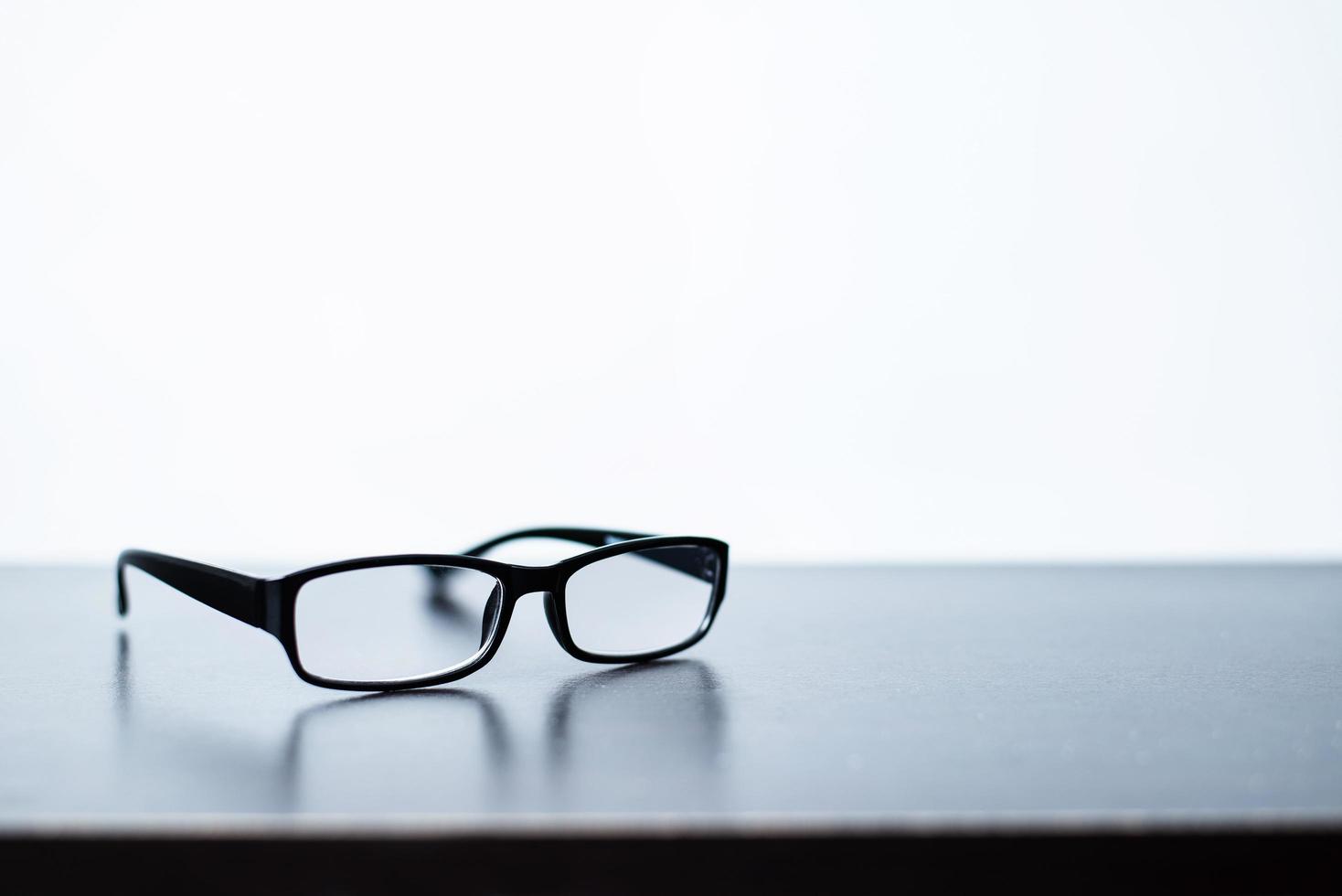 bril geplaatst Aan de bureau met wit achtergrond foto