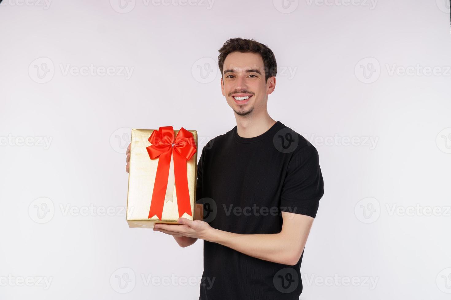 portret van gelukkig jong Kaukasisch Mens tonen Cadeau doos en op zoek Bij camera geïsoleerd over- wit achtergrond. verjaardag partij concept. foto