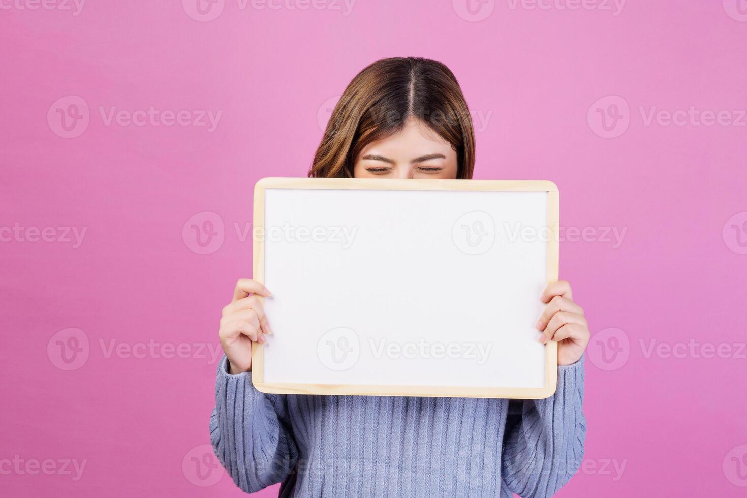 portret van gelukkig jong vrouw Holding een leeg wit aanplakbiljet over- geïsoleerd roze achtergrond. foto