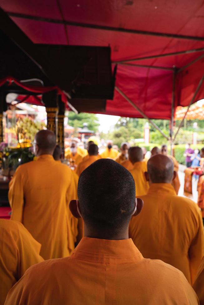 bandoeng, Indonesië, 2020 - de monniken in oranje beroven staand in bestellen terwijl bidden naar de god Bij de altaar binnen de Boeddha tempel foto