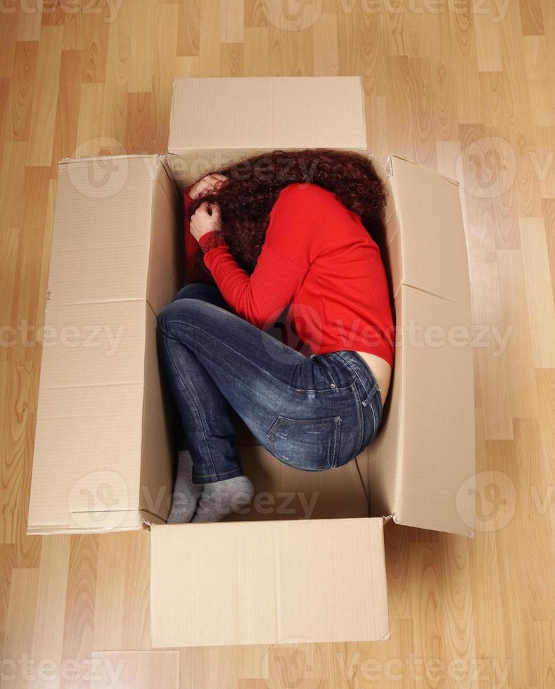 meisje aan het liegen gekruld omhoog in karton doos foto