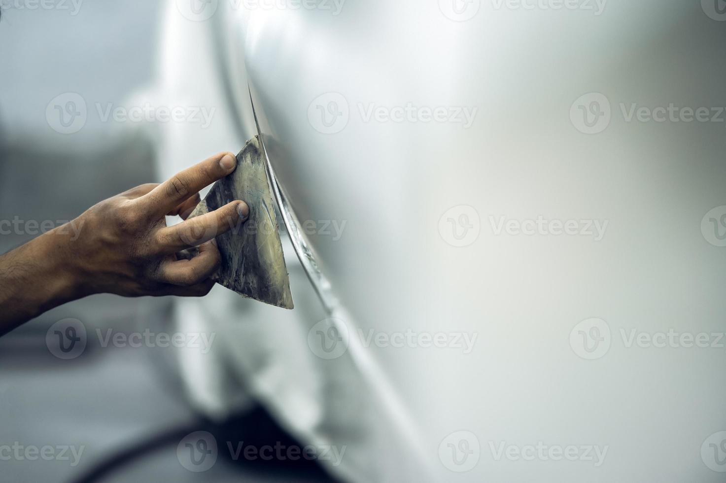 een geschoold schilder detaillering een professioneel auto verf primer terwijl polijsten een glimmend wit auto, auto detaillering, auto wassen en verf reparatie. bijgesneden beeld selectief focus foto