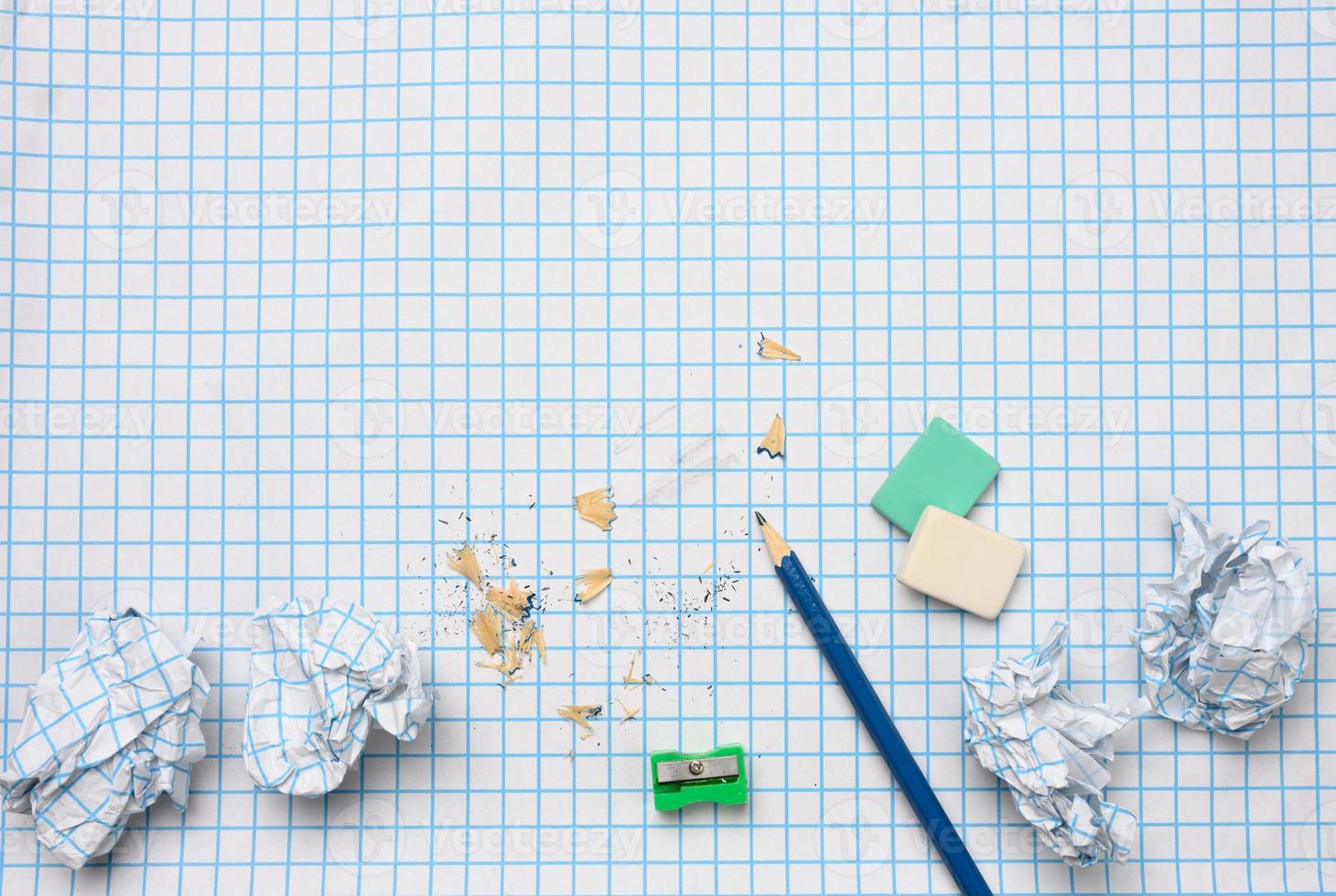 verfrommeld papier ballen en een geslepen houten potlood met krullen Aan een geruit papier vel foto