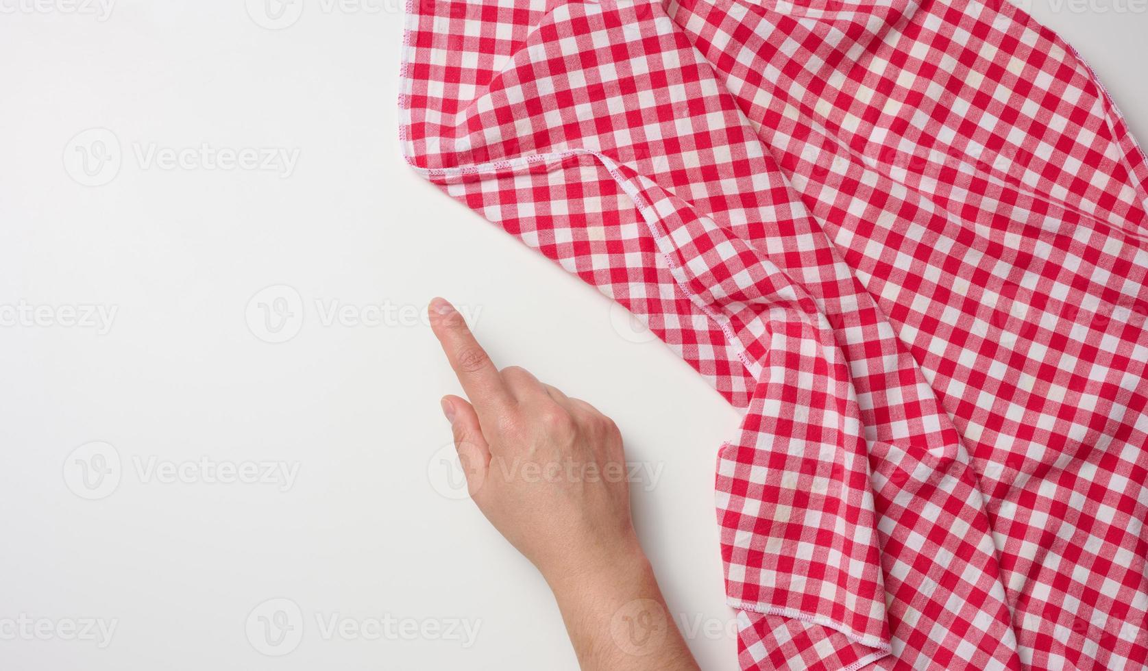 vrouw hand- met verheven wijsvinger en rood keuken servet Aan wit tafel, top visie foto