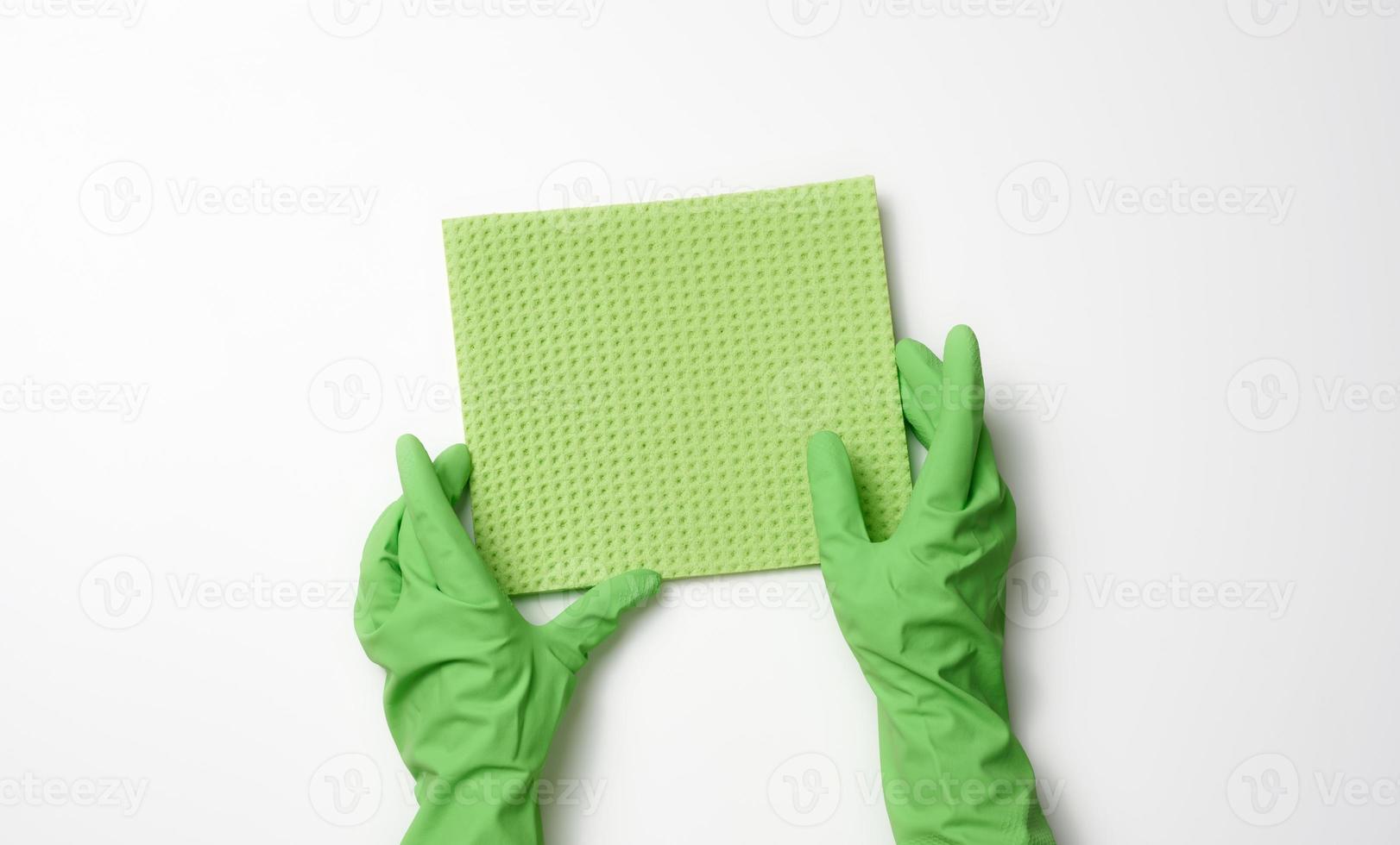 hand- in een groen rubber handschoen houdt een zacht spons voor schoonmaak oppervlakken Aan een wit achtergrond foto
