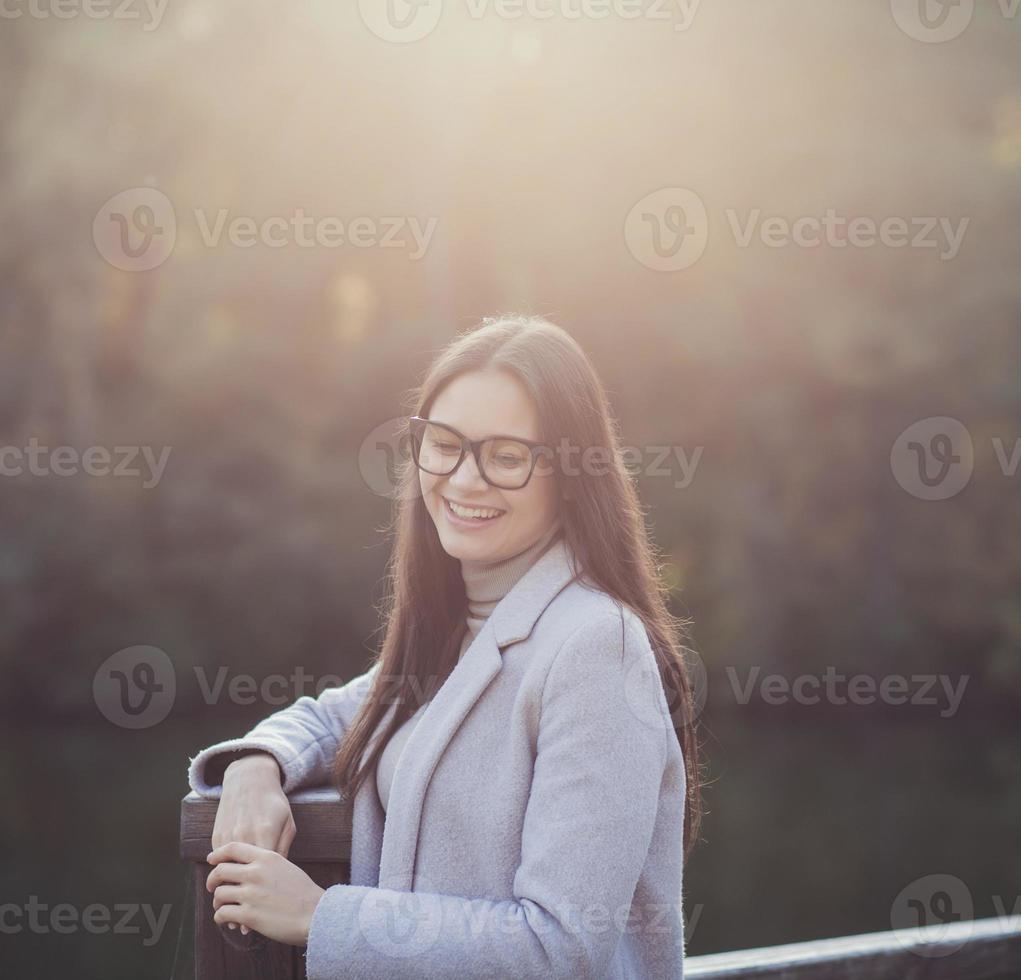 vrouw in jas glimlacht Bij zonsondergang foto