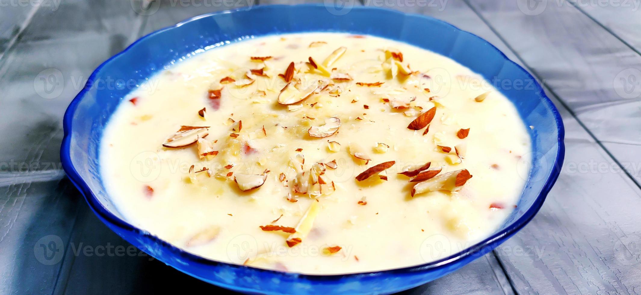 zoet rabdi of lachha rabri of basundi, gemaakt met zuiver melk gegarneerd met droog vruchten. geserveerd in een kom over- humeurig achtergrond. foto