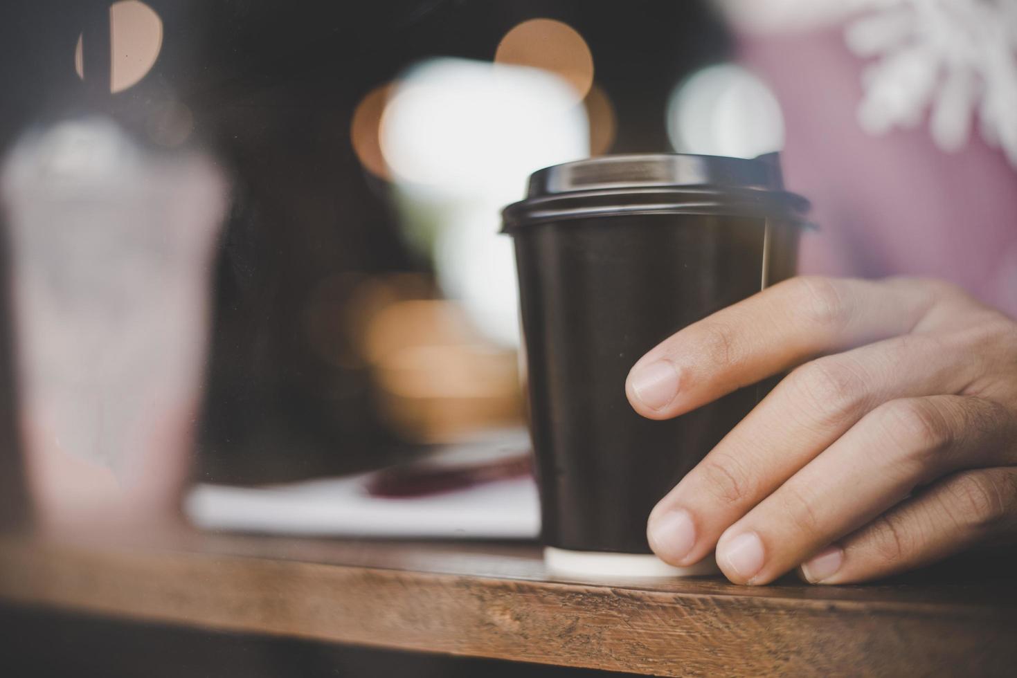 close-up van jonge man met koffie om mee te nemen in café foto