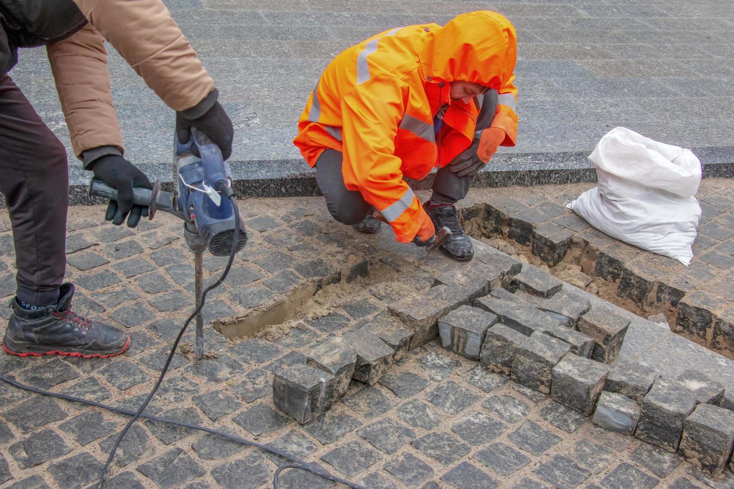 dnjepropetrovsk, Oekraïne - 02.10.2022 een mannetje arbeider reparaties de bestrating met een drilboor. de werk van de gemeentelijk onderhoud. foto