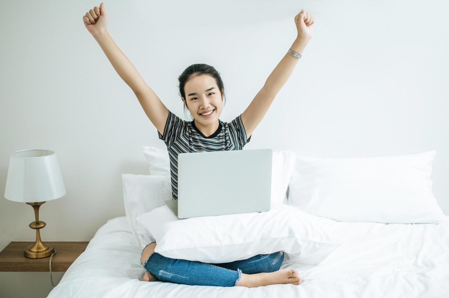 een jonge vrouw die op haar laptop in bed speelt foto