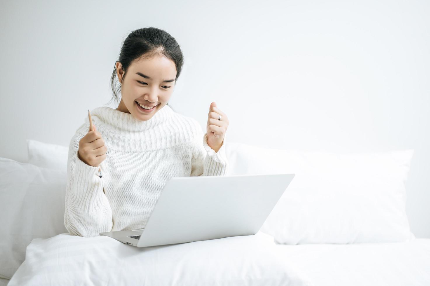 jonge vrouw die een wit overhemd draagt dat op haar laptop speelt foto